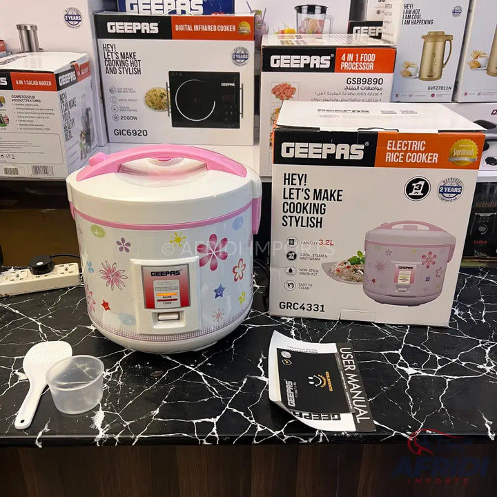 A white electric rice cooker with pink floral patterns and a pink handle.
