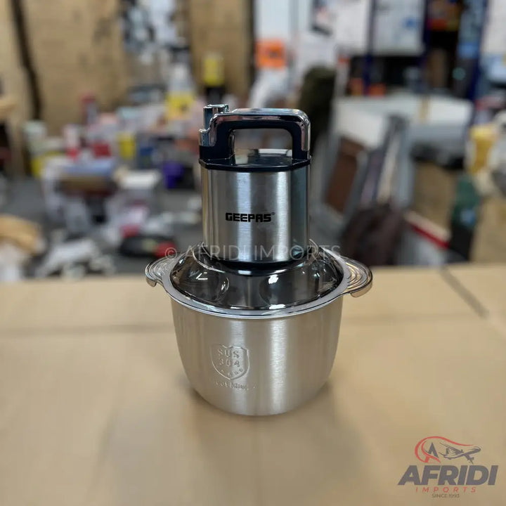 A stainless steel electric food chopper with a black handle.