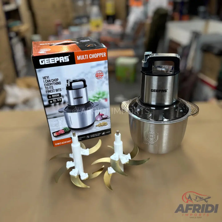 A silver multi-chopper with two sets of blades and its packaging.