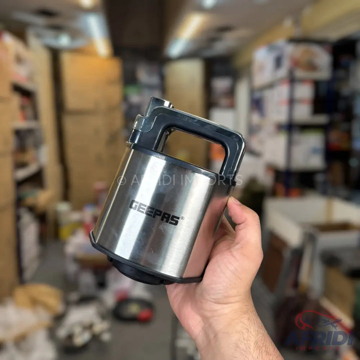 A stainless steel electric coffee grinder with a black handle.