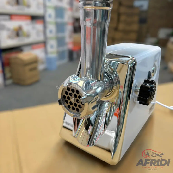 A shiny, white electric meat grinder with chrome accents and a perforated grinding plate.