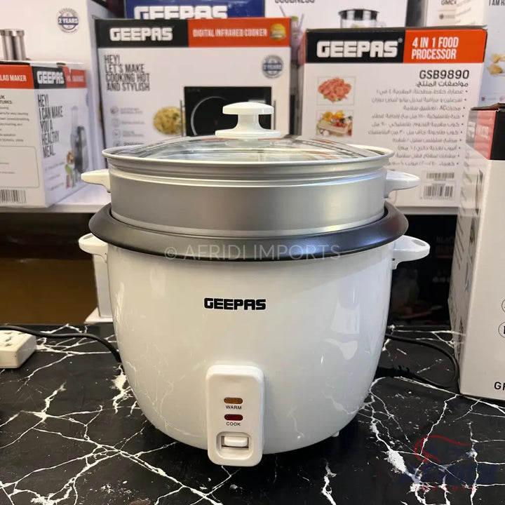 White electric rice cooker with a transparent lid and a steamer insert.