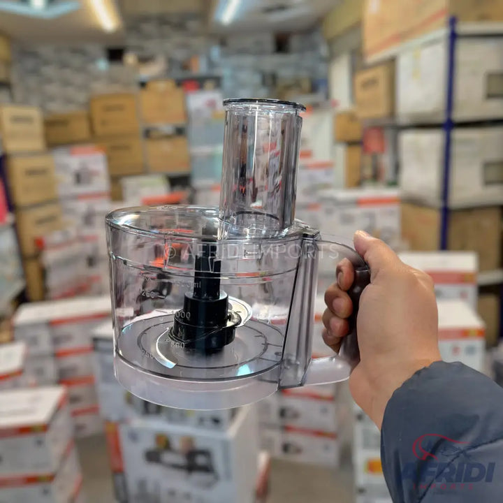 Clear plastic food processor bowl with a handle and feed chute, containing a blade assembly.