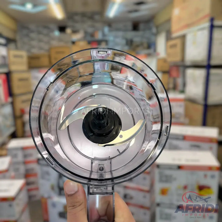 A clear plastic food processor chopping bowl with a two-pronged blade.