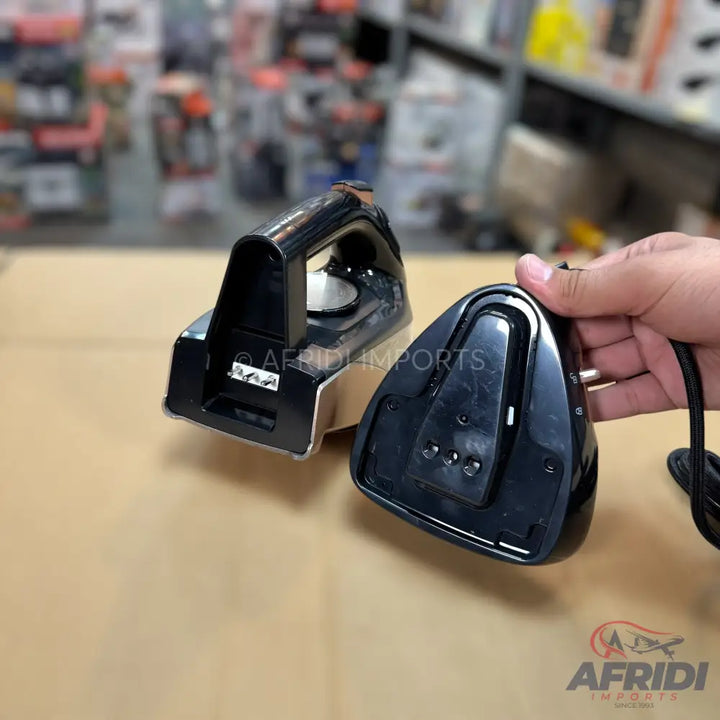 A black and silver cordless travel iron with a separate charging base.
