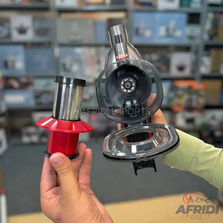 A handheld vacuum cleaner with its washable filter removed for cleaning.