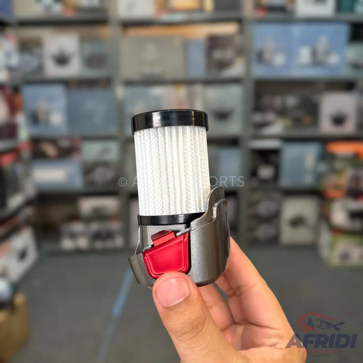 A cylindrical vacuum cleaner filter with a pleated white mesh and a red release button on its grey housing.