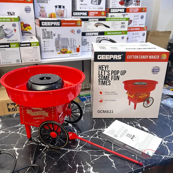 Red retro-style cotton candy maker with wheels and a long handle.