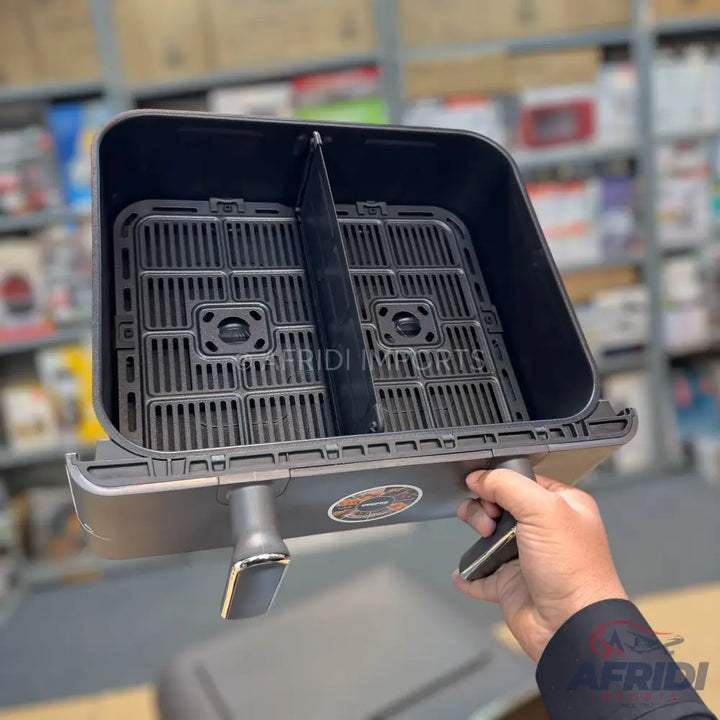 Black air fryer basket with a removable divider and handle.