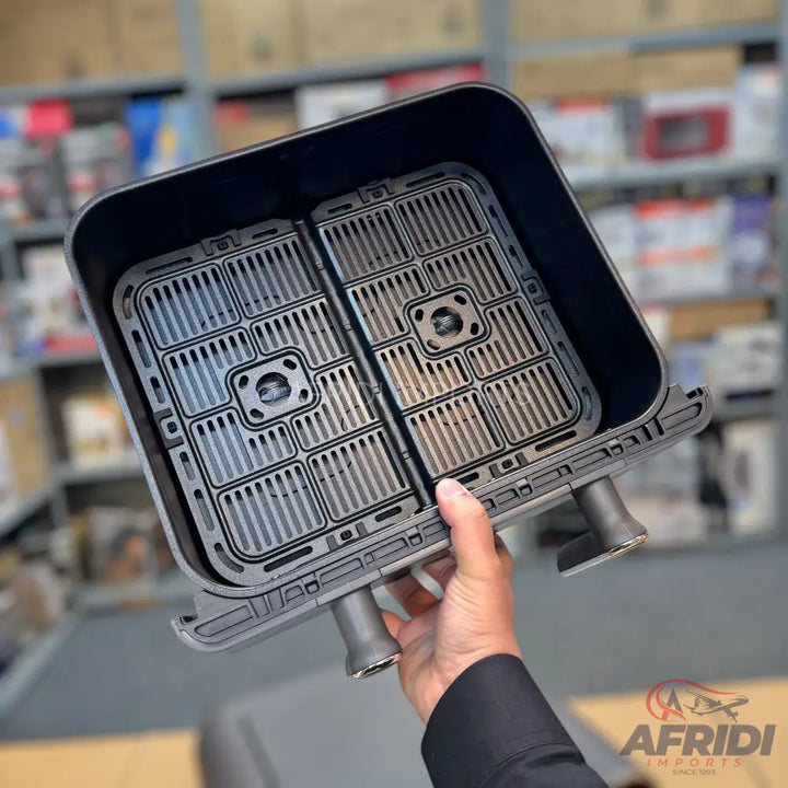 A black air fryer basket with a removable two-compartment divider and two handles.
