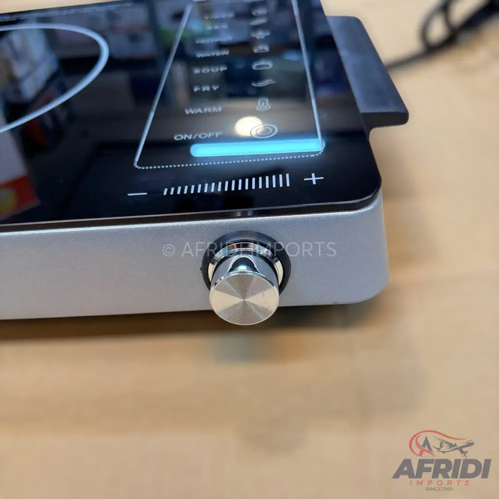 Modern induction cooktop with a digital display, touch controls, and a prominent silver knob for adjustment.