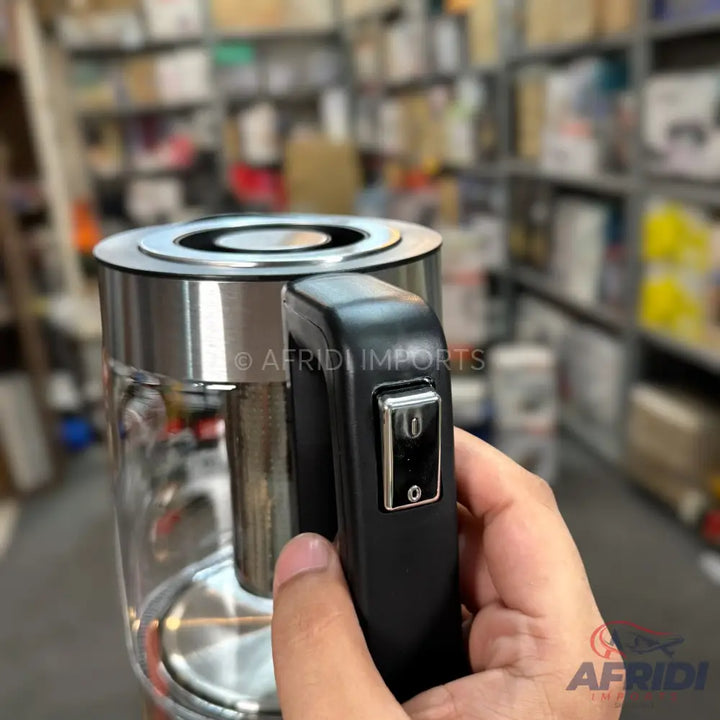 A glass electric kettle with a black handle and a metallic base.