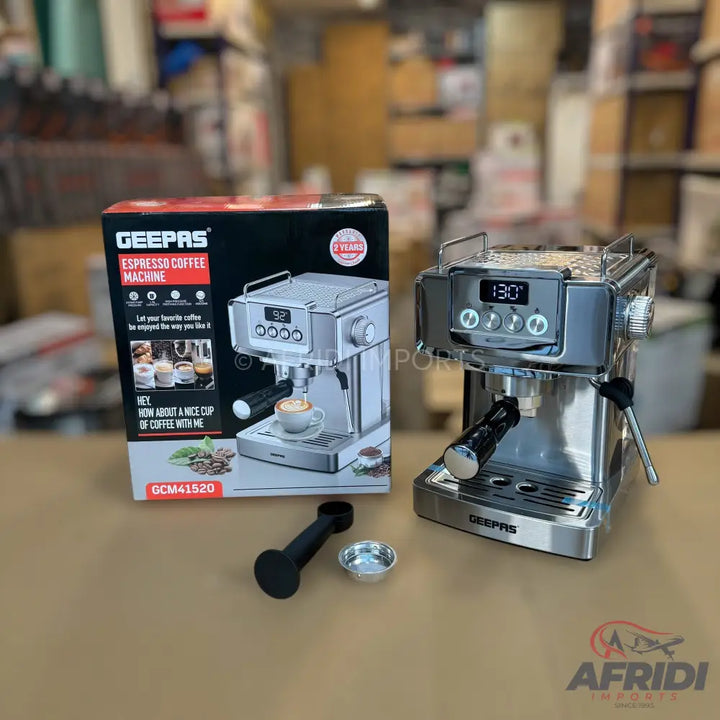 A silver Geepas espresso coffee machine with a digital display and various buttons, accompanied by its packaging, a portafilter, and a filter basket.