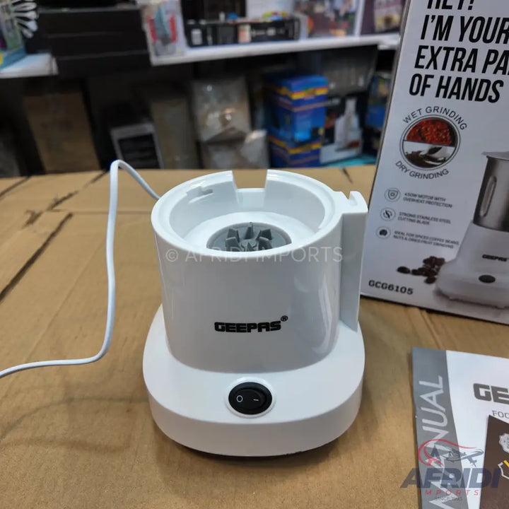 White electric coffee grinder with a visible on/off switch and internal grinding blades.