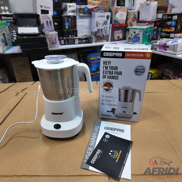 White and stainless steel food processor with a handle, lid, and power button, accompanied by its packaging and user manual.