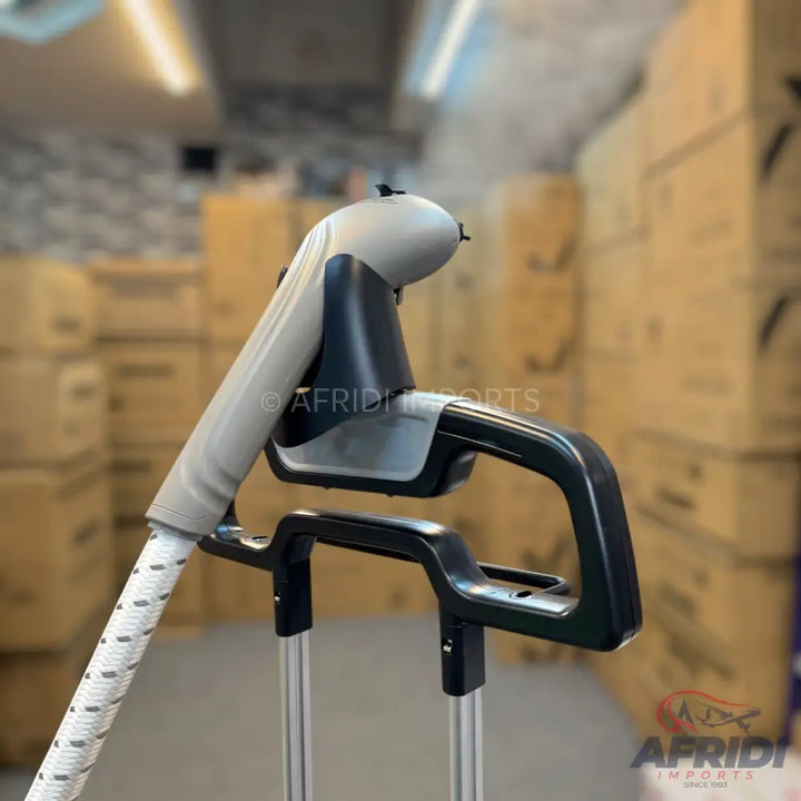 A garment steamer with a white hose and a gray and black head, emitting steam.