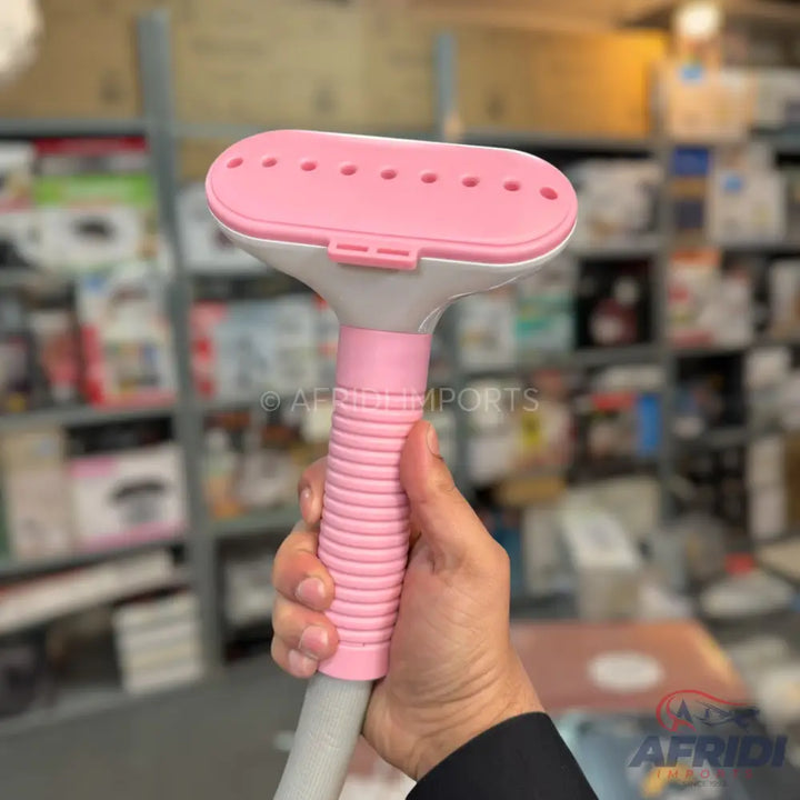 Pink and white handheld garment steamer with a ribbed handle.