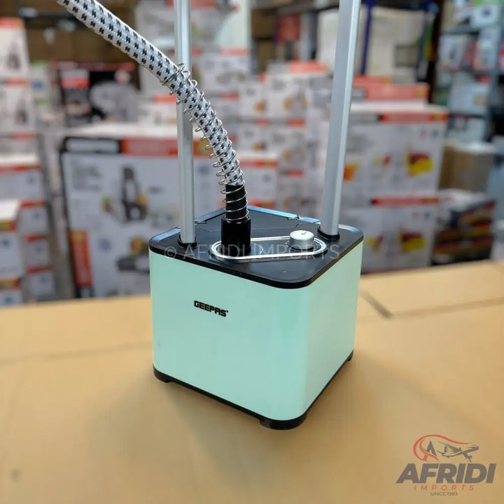 Mint green garment steamer with a black top and a flexible hose.