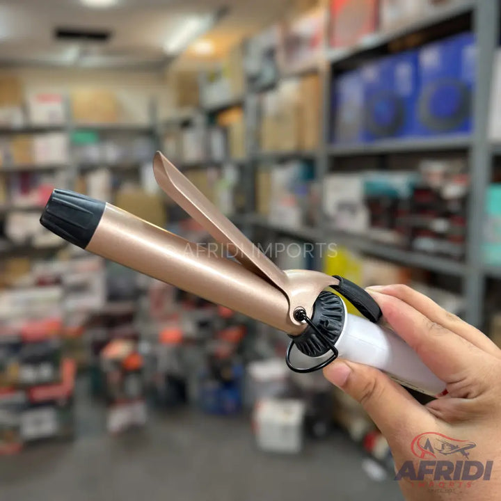 Rose gold hair curling iron with a white handle.