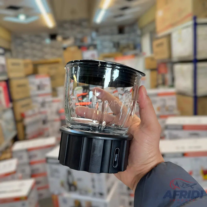 A clear glass blender jar with a black base and lid, featuring visible measurement markings and a power button on the base.