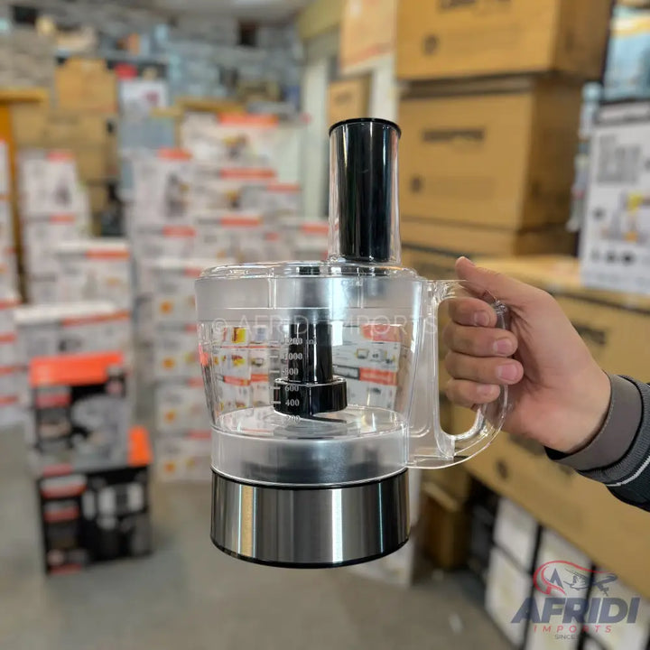 A clear plastic food processor with a stainless steel base and a black lid.