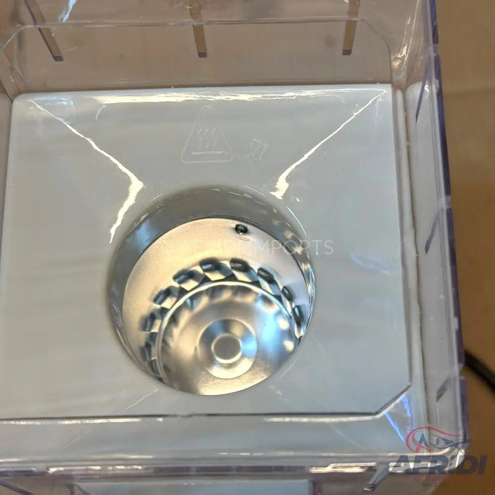 A transparent plastic container with a metallic, dome-shaped object inside.