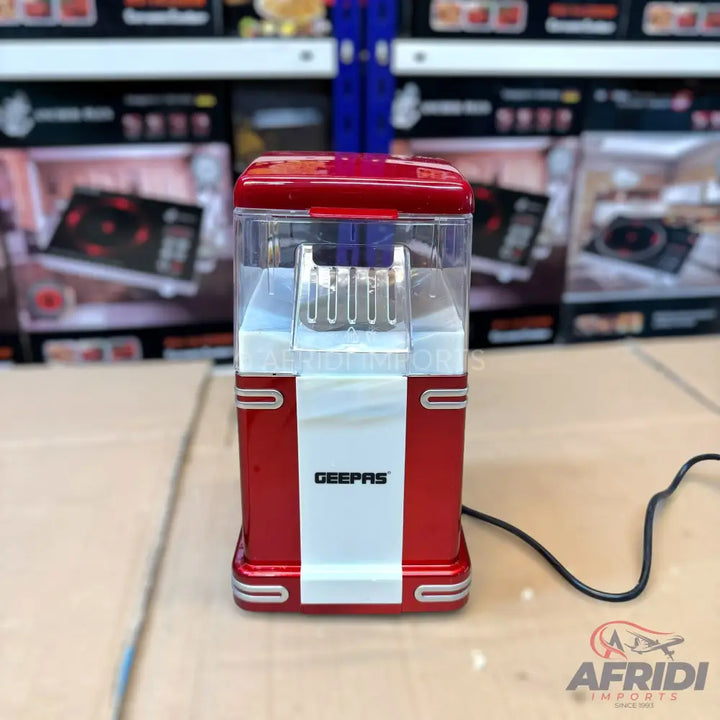 Red and white electric popcorn maker with a clear top.