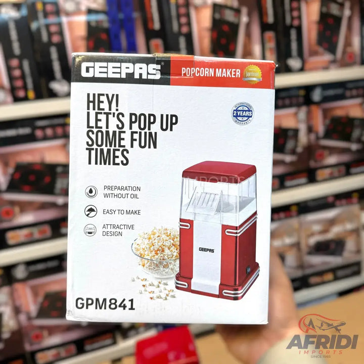 Red and white countertop popcorn maker with a transparent top.