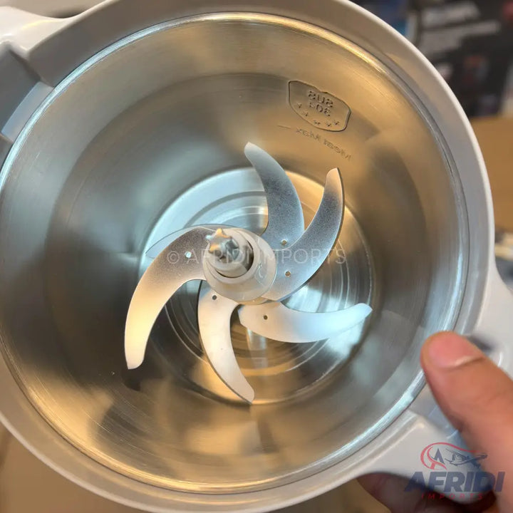 A shiny metallic blender or grinder cup with a four-blade assembly.