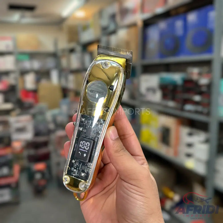 A gold and clear electric hair clipper with a digital display showing ’100’’.