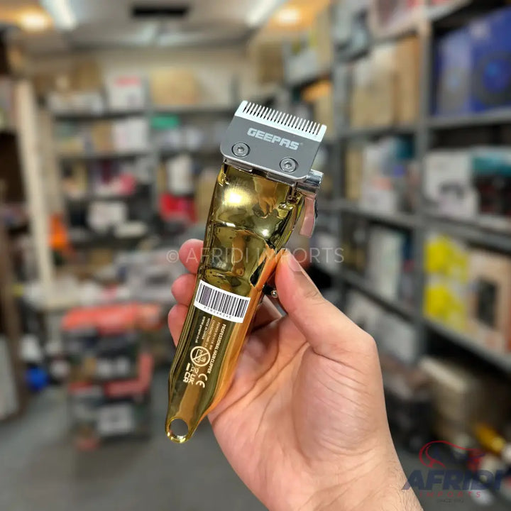A shiny, gold-colored electric hair clipper with a silver blade.