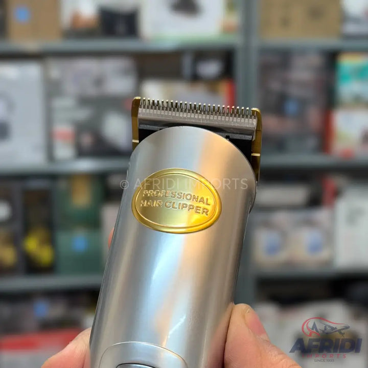 Silver professional hair clipper with a gold-colored emblem.