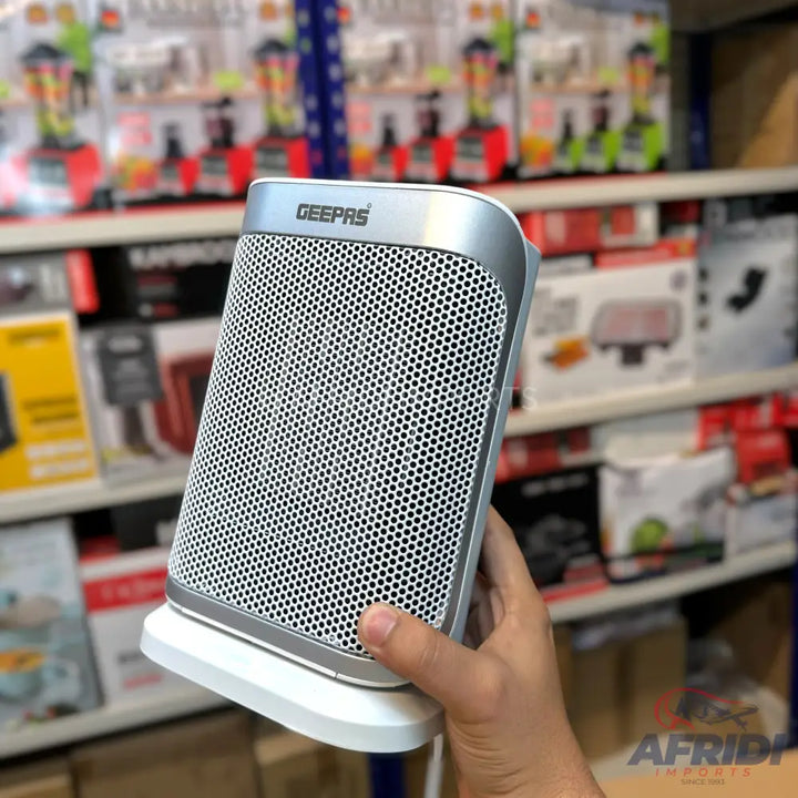A silver and white electric space heater with a perforated front grille.