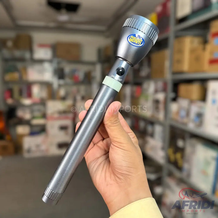 A silver-colored, textured grip flashlight with a blue and yellow emblem on the head.