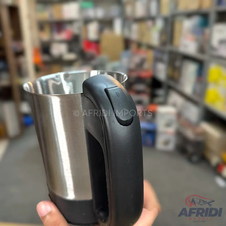 A stainless steel electric kettle with a black handle and lid release button.