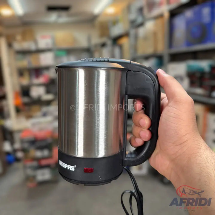 A stainless steel travel electric kettle with a black handle and base.