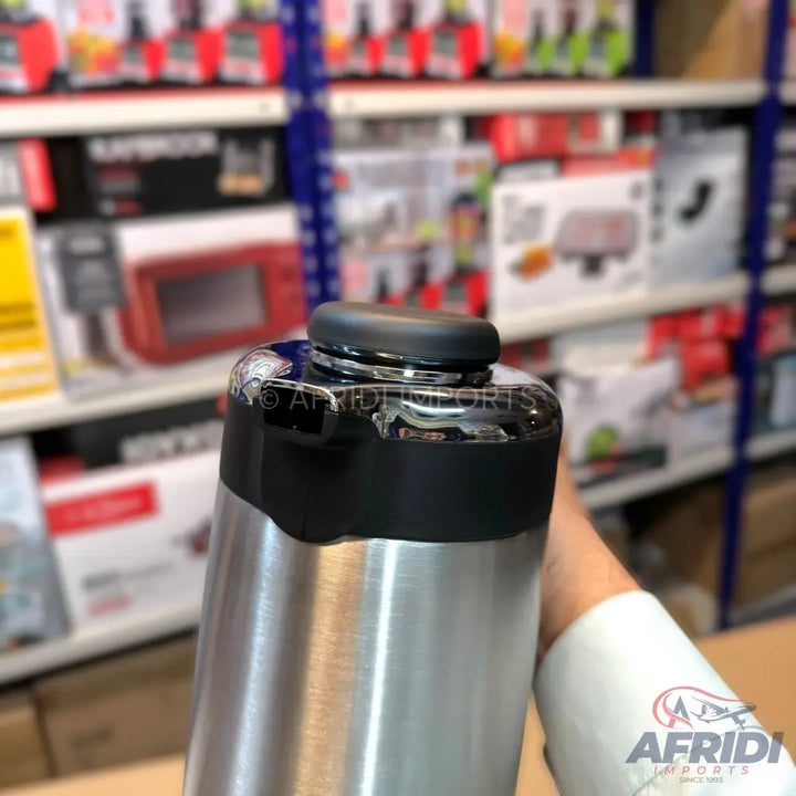 A shiny, stainless steel thermal flask with a black top.