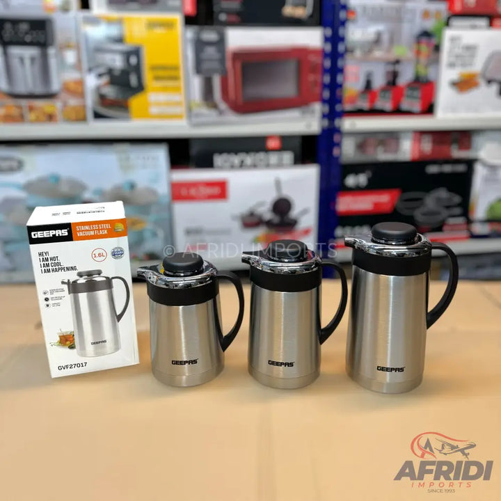 A set of three stainless steel vacuum flasks with black handles and push-button lids.