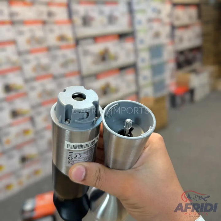 A hand holding a disassembled electric pepper grinder, showing the motor unit and the grinding mechanism.