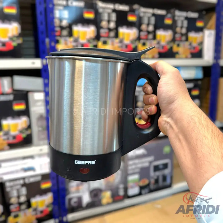 Stainless steel electric travel kettle with a black handle and base.