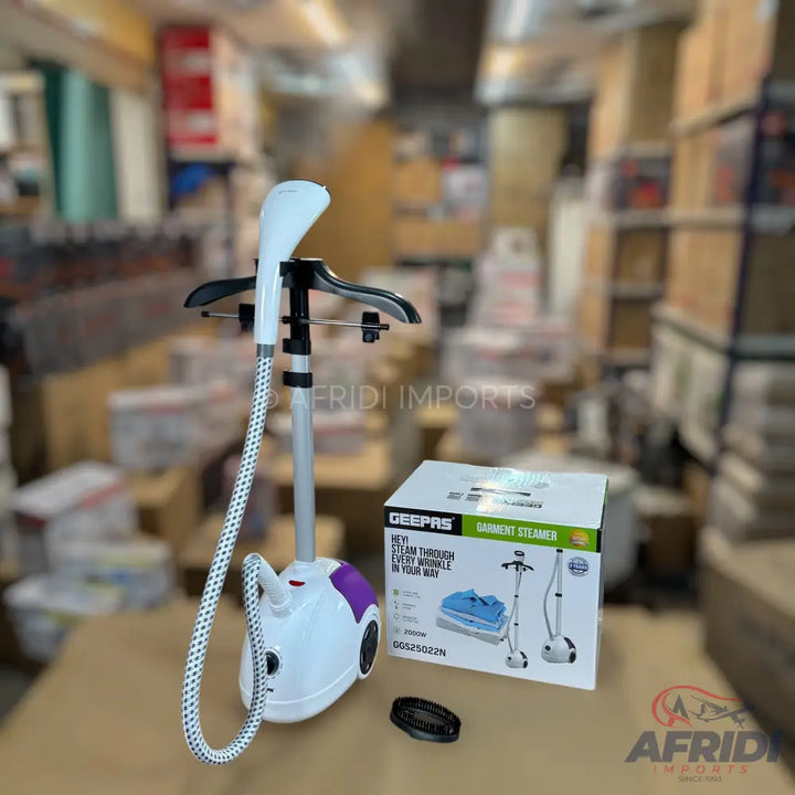 A white and purple garment steamer with an adjustable stand and a hose, accompanied by its packaging.