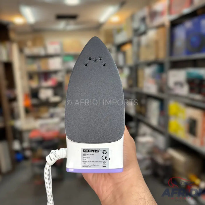 A compact travel iron with a grey soleplate and a white body.