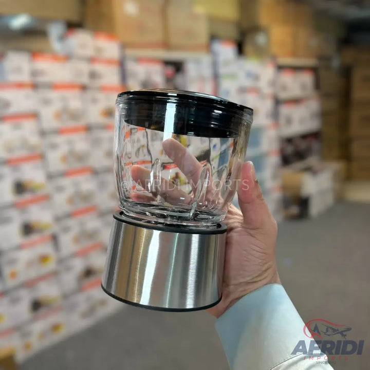 A clear glass blender jar with a black lid and a stainless steel base.
