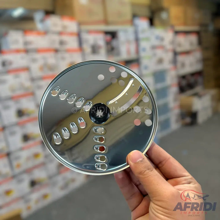 A shiny, round, multi-purpose food processor blade with various grater and shredder holes.