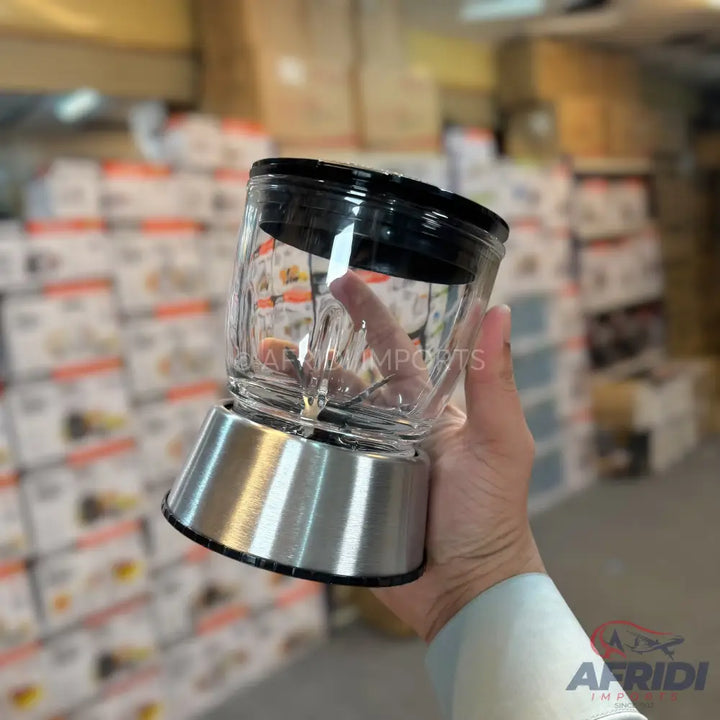 A compact electric food chopper with a clear glass bowl, a black lid, and a stainless steel base.