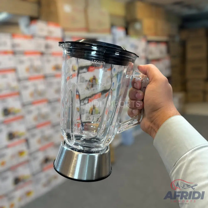 A clear glass blender jar with a black lid and a silver base.