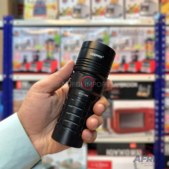 A black, ribbed, handheld flashlight with a red power button.