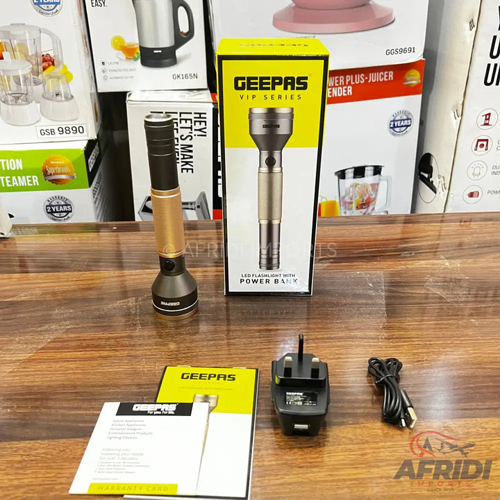 A Geepas LED flashlight with power bank functionality, accompanied by its charging adapter, cable, and user manual.