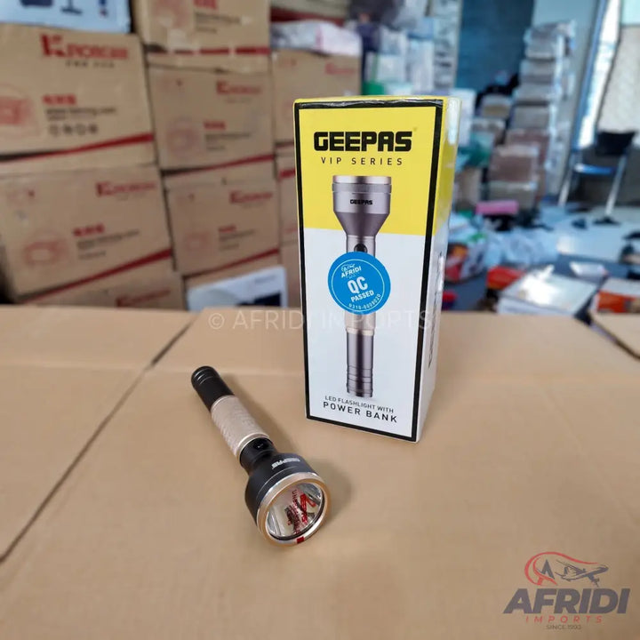 A black and gold flashlight with a red-tipped bulb and a white box for a Geepas VIP Series LED flashlight with a power bank.