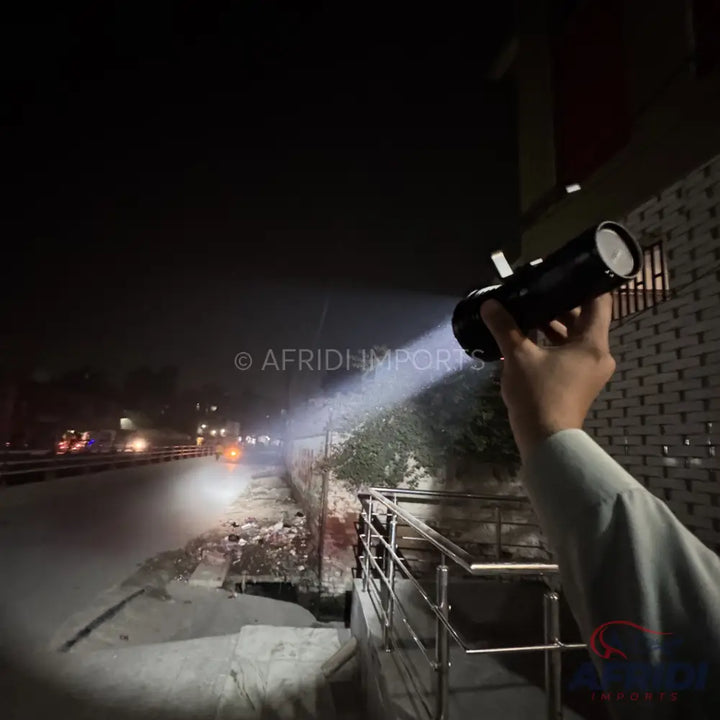 A black, cylindrical handheld flashlight emitting a powerful beam of white light.